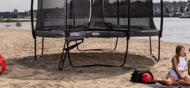 Banner mit BERG Elite Regular Trampolin am Strand mit entspannenden Menschen