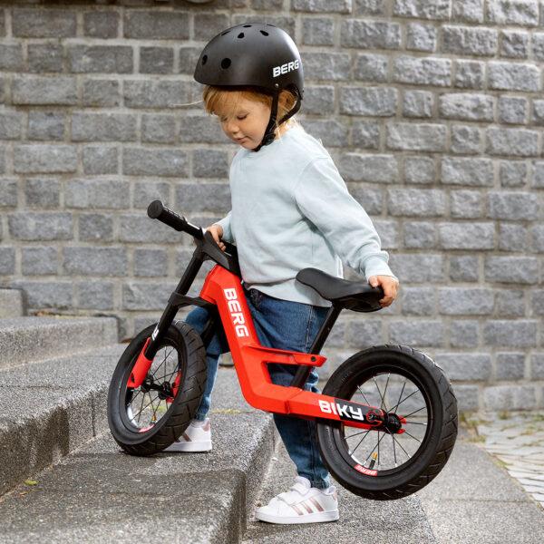 Enfant soulève le vélo d’équilibre BERG Biky léger sur les escaliers, maniable et facile à transporter