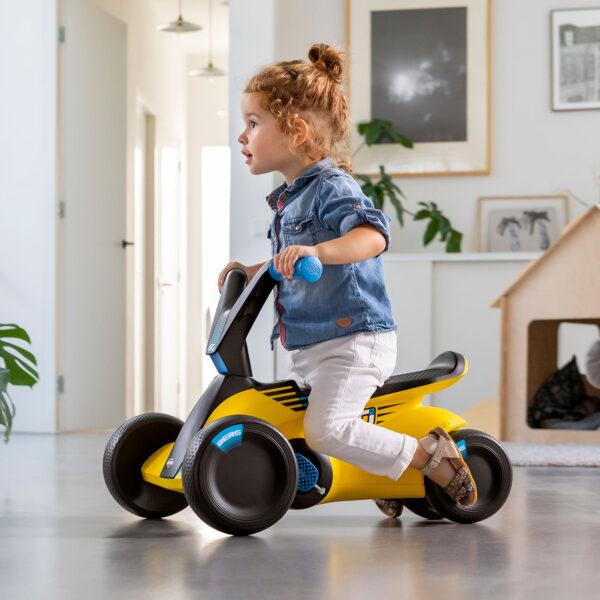 Toddler rides the yellow BERG GO² ride-on car indoors