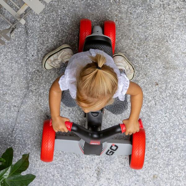 Toddler drives the BERG GO² ride-on car with red wheels from above