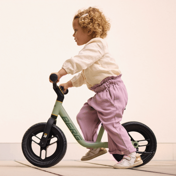 Toddler rides a BERG MOOV 10 balance bike indoors