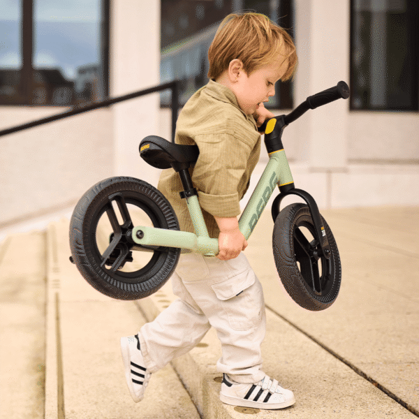 Toddler carries a lightweight BERG MOOV 10 balance bike