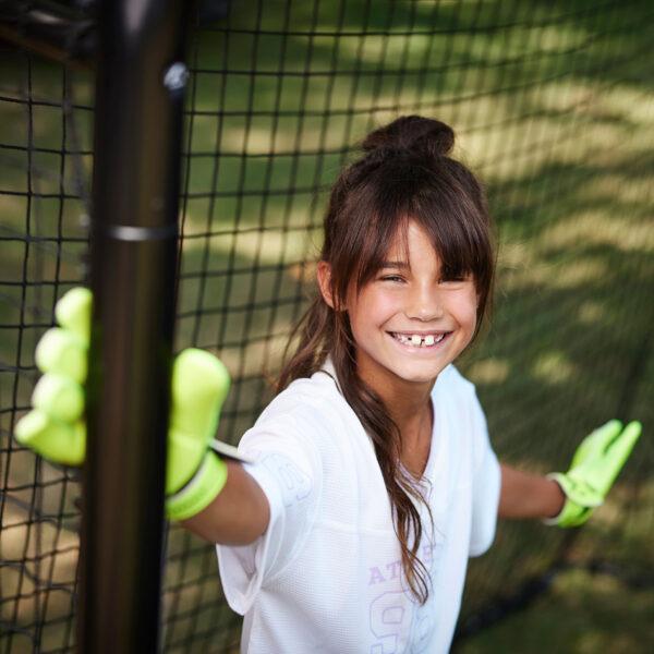 Ragazza con guanti da portiere vicino a una porta da calcio BERG SportsGoal in giardino