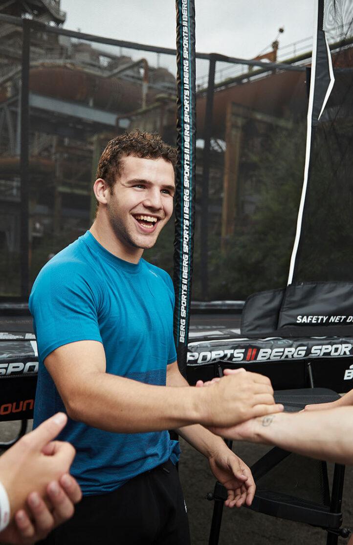 Young people laughing and shaking hands near a BERG trampoline during MOB Masters of Bounce