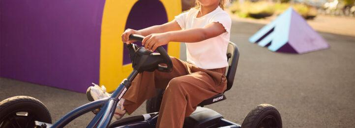 Child rides a BERG Buddy Classic Blue go-kart and smiles