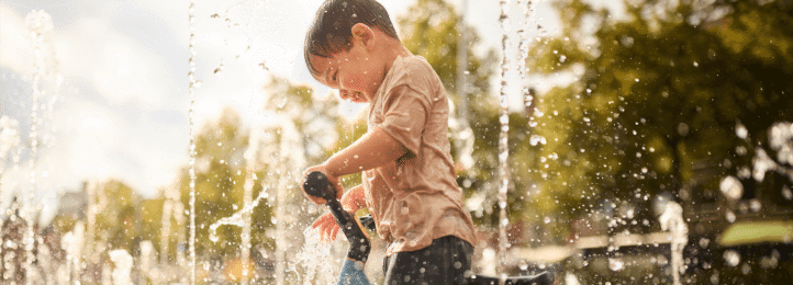 Child plays with a BERG MOOV 7 balance bike near fountains