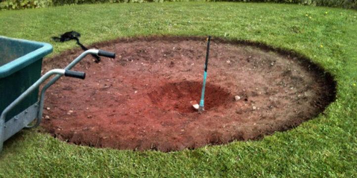 Uitgegraven kuil in het gras als voorbereiding voor de installatie van een BERG inground trampoline