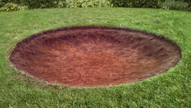 Dug-out pit in the grass as preparation for installing a BERG inground trampoline