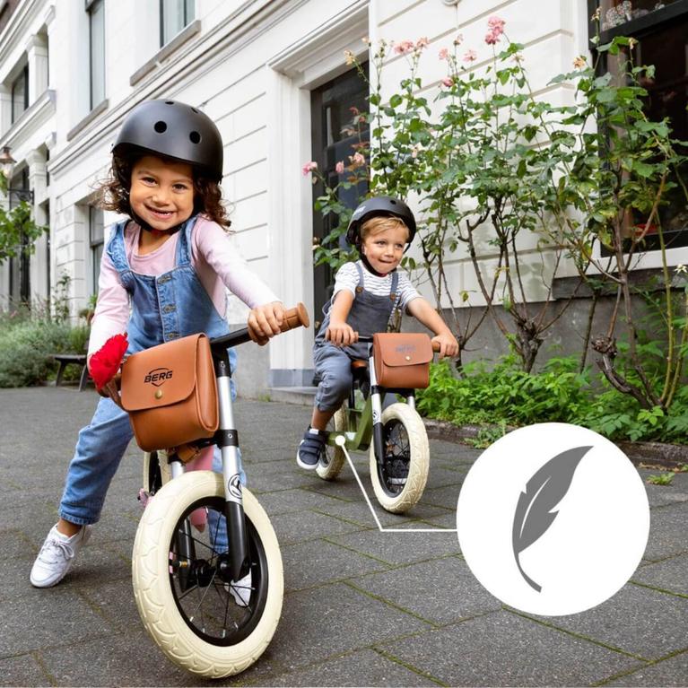 Two children riding a lightweight BERG Biky Retro balance bike in the city