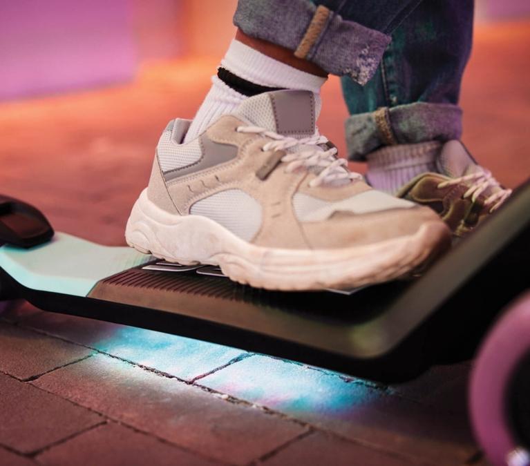 Close-up of a foot on a BERG Nexo scooter with illuminated deck for extra visibility