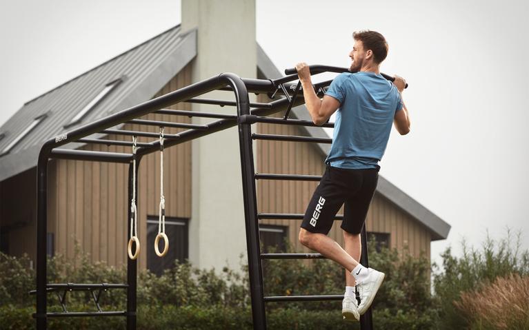 Man doing pull-ups on a BERG PlayBase climbing frame with pull-up bar