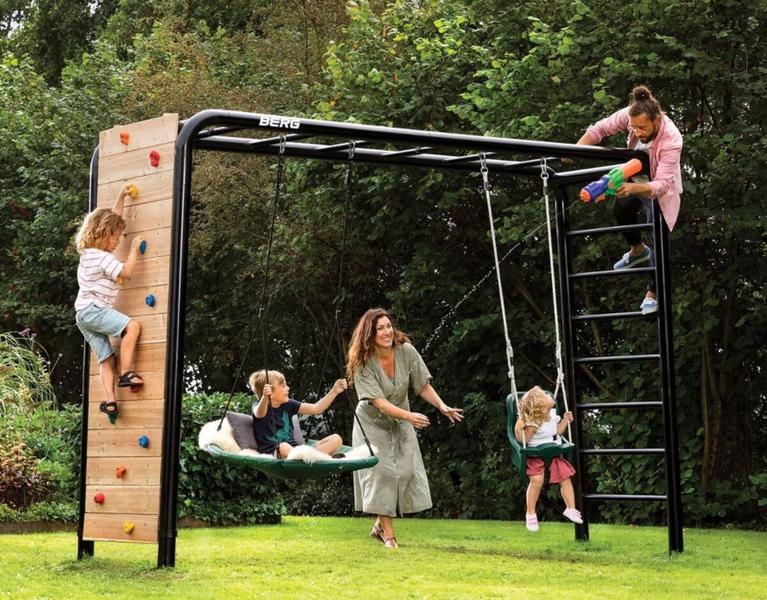 Children playing on a BERG PlayBase climbing frame with swing in the garden