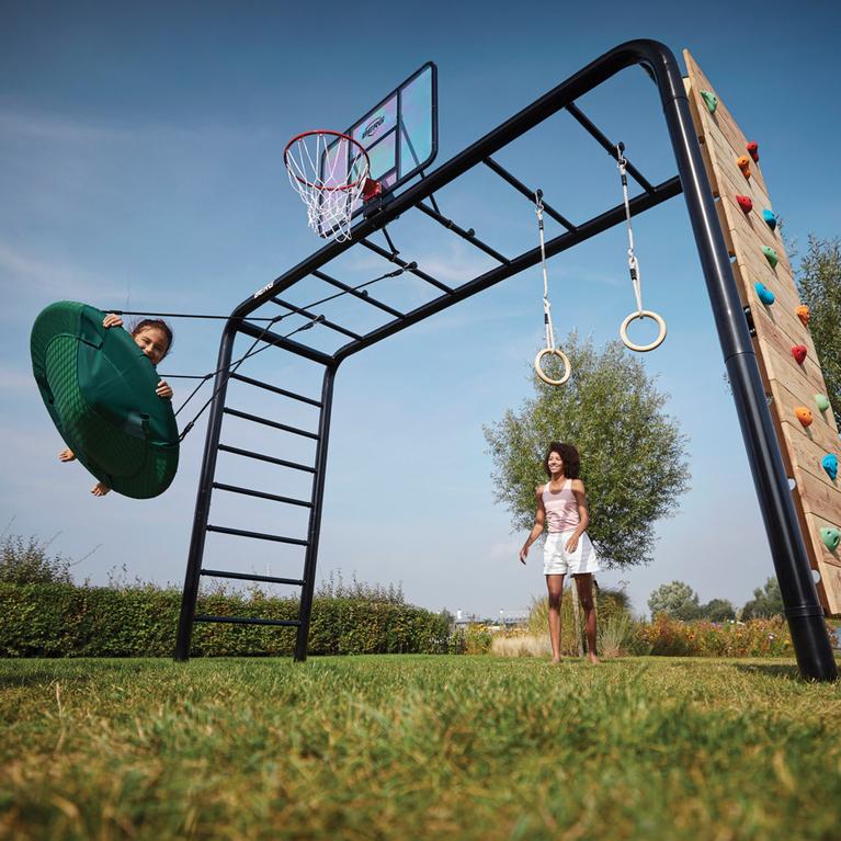 Children playing on a BERG PlayBase climbing frame with nest swing, gymnastic rings, basketball hoop and climbing wall