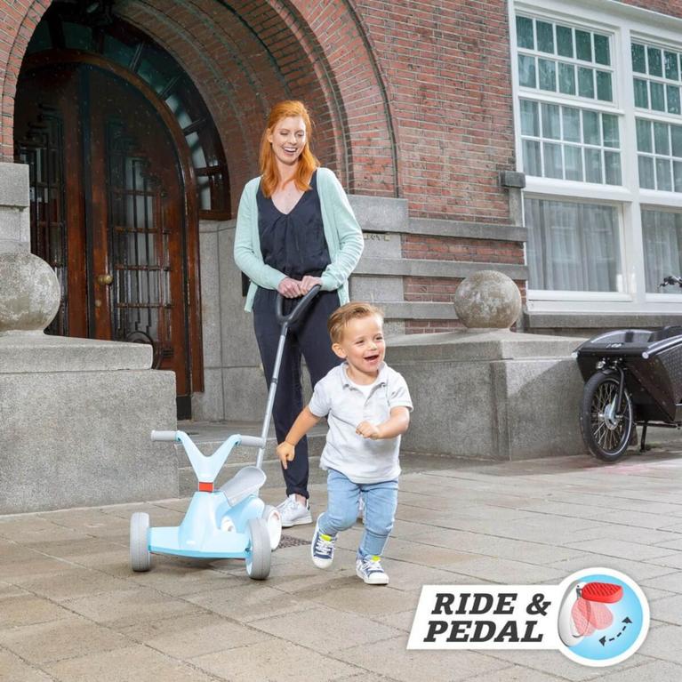 Child running happily in front of a blue BERG GO ride-on car with push bar, pushed by parent