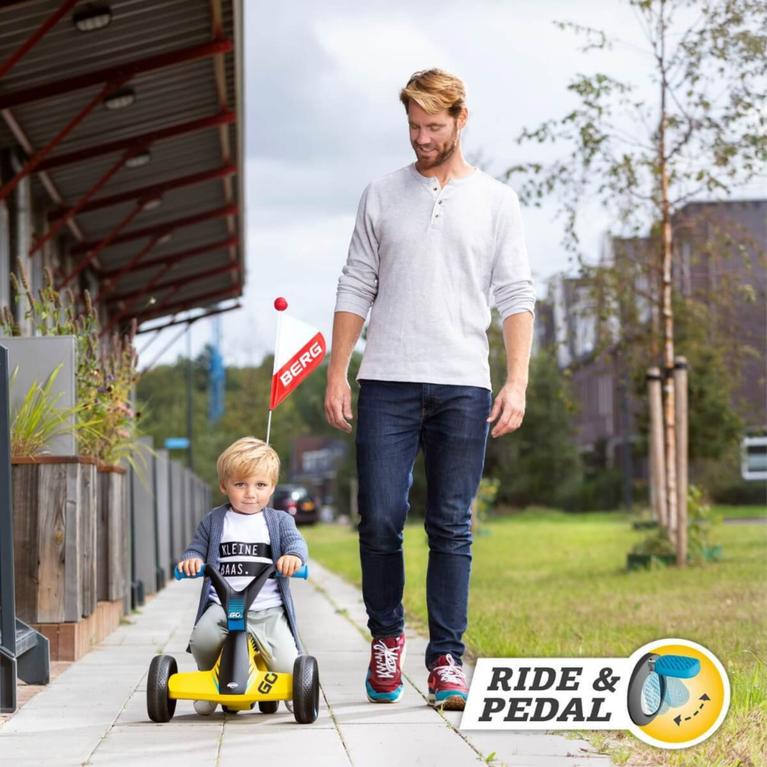 Enfant sur une voiture à pousser BERG GO jaune avec parent marchant à côté