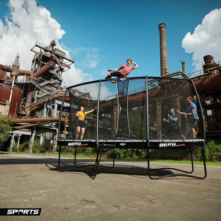 Gruppe Jugendlicher spielt und entspannt auf einem BERG Pro Bouncer Trampolin in einer industriellen Umgebung