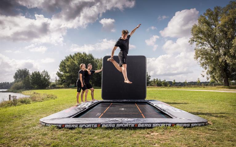 Junge springt auf einem BERG FlatGround Trampolin Sports mit Stuntwand in einem Park