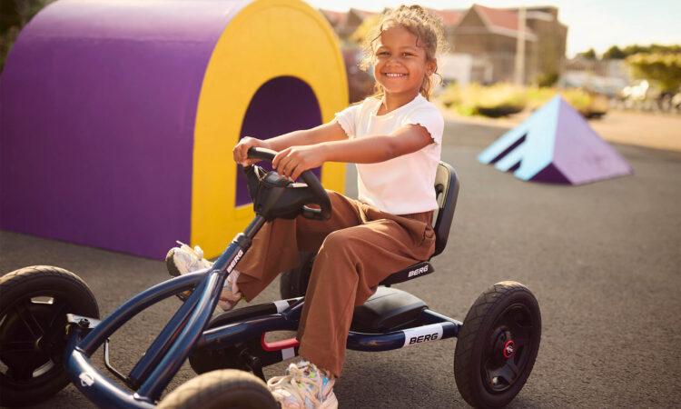 Kind fährt einen BERG Buddy Classic Blue Gokart und lächelt