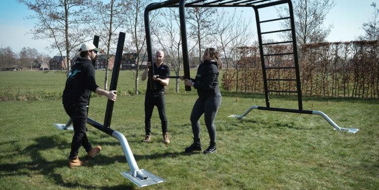 Step 1: Team starts assembling a BERG PlayBase climbing frame on a grass field