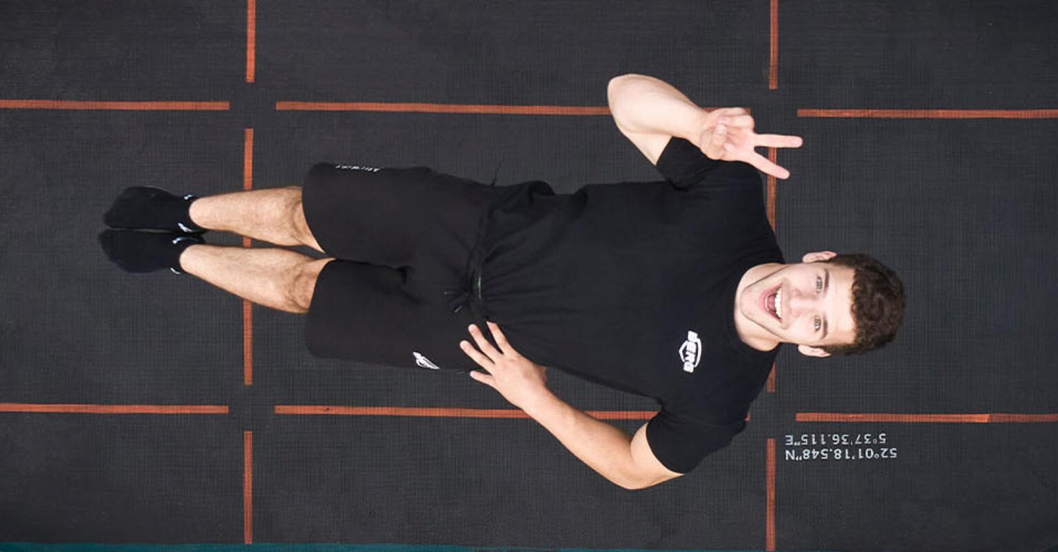 Saltador profesional realiza un salto en el aire en un trampolín BERG Pro Bouncer Sports, vista superior, banner