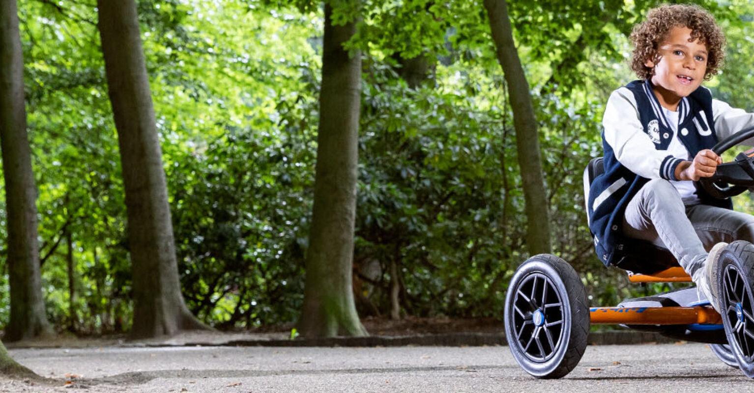 Child driving a BERG go-kart through the forest – banner