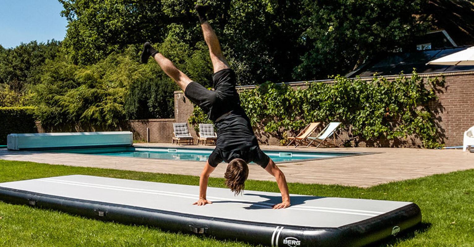 Person does a handstand on a BERG AirTrack in a garden