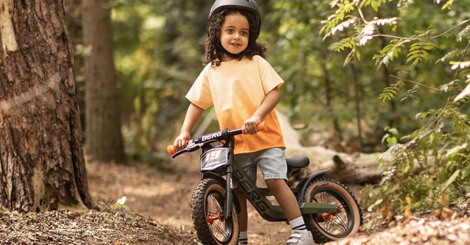 Niños montando una bicicleta de equilibrio BERG Biky por el bosque – banner