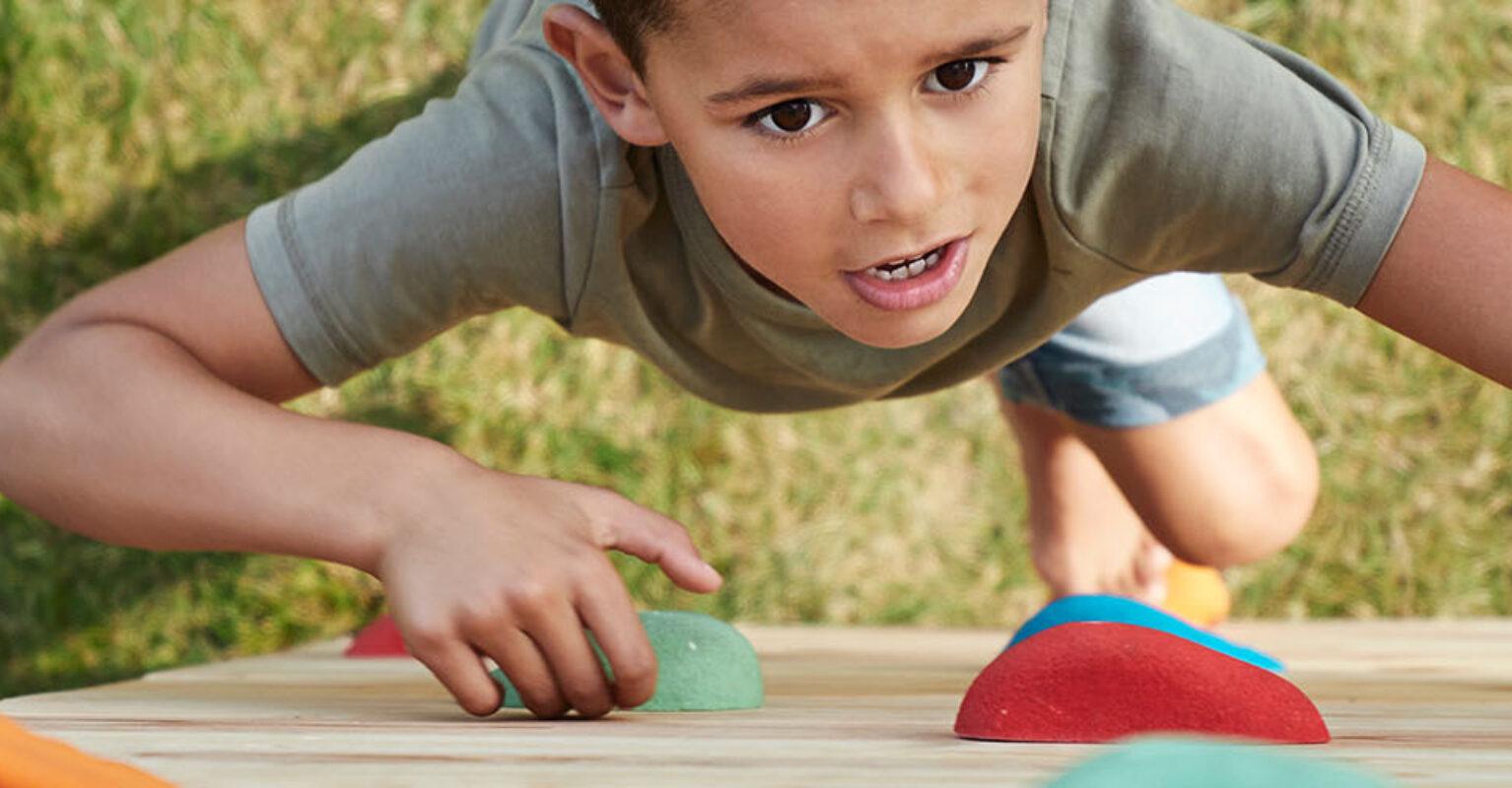 Child climbing on a BERG PlayBase climbing frame with wooden climbing wall – banner