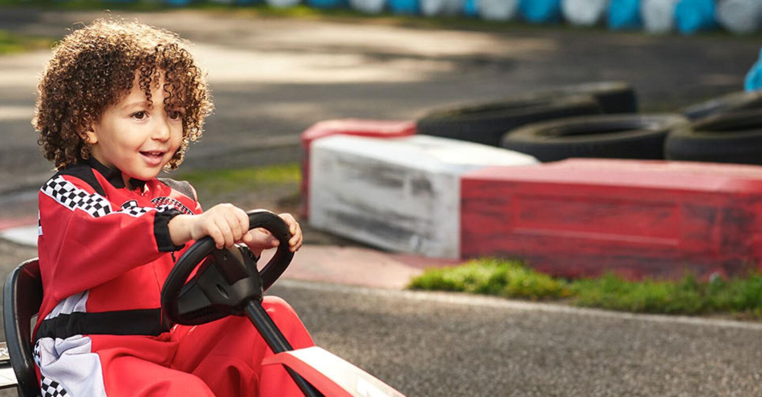 Child in red racing suit drives a BERG Reppy go-kart on a track